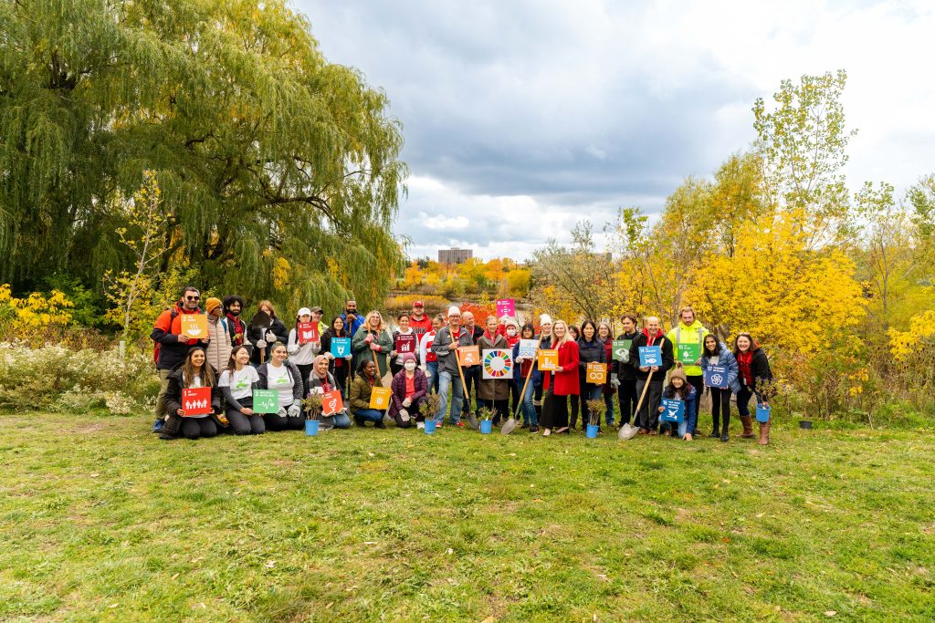 York University community members pictured after tree planting event, holding shovels and signs representing the 17 United Nation Sustainable Development Goals.”