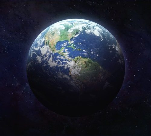 The planet earth in space is lit on the top half of the planet and dark on the bottom half.