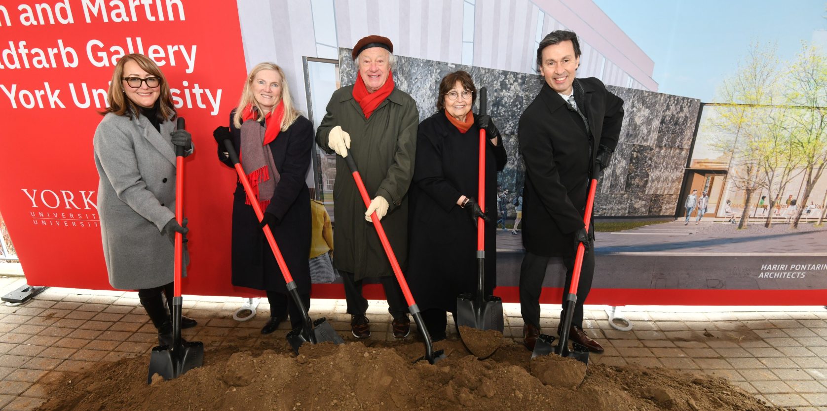 5 people with red shovels break ground in front of a York University banner.